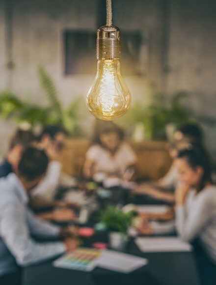 Young creative business people meeting at office. Young business people are discussing together a new startup project. A glowing light bulb as a new idea.